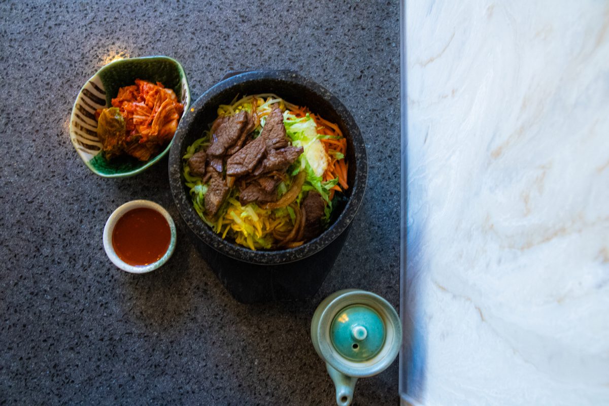 A bowl of Dol Sot Bibimbop with beef bulgokee steams next to a serving of napa cabbage kimchi at KoFusion in Champaign on Feb. 27. The restaurant offers a range of Asian fusion cuisine, including several Korean staples.