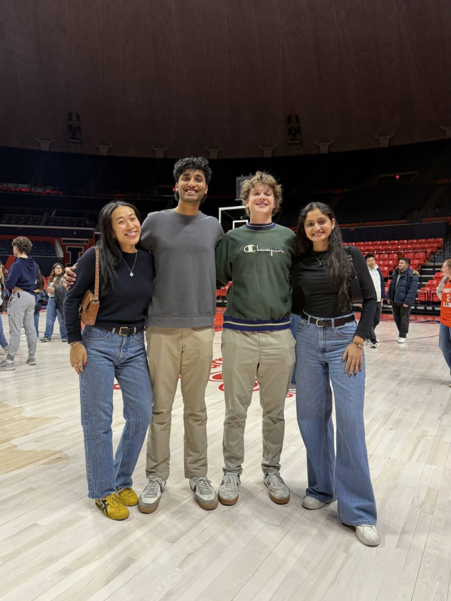 Christine Leung, Lalit Gurrapu, Owen Krajecki and Dhwani Patel pose for a photo at the State Farm Center at a basketball game they were invited to watch courtside by the Gies College of Business.