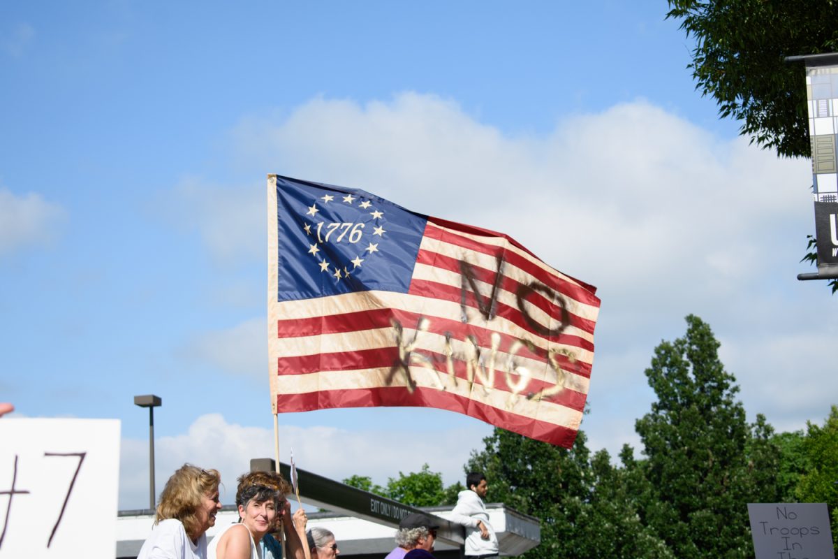 A protestor holds a 1776 American flag with the words "No Kings" spray painted across the stripes on June 14, 2025. Champaign County Indivisible announced the third iteration of the "No Kings" protest will take place on March 28.