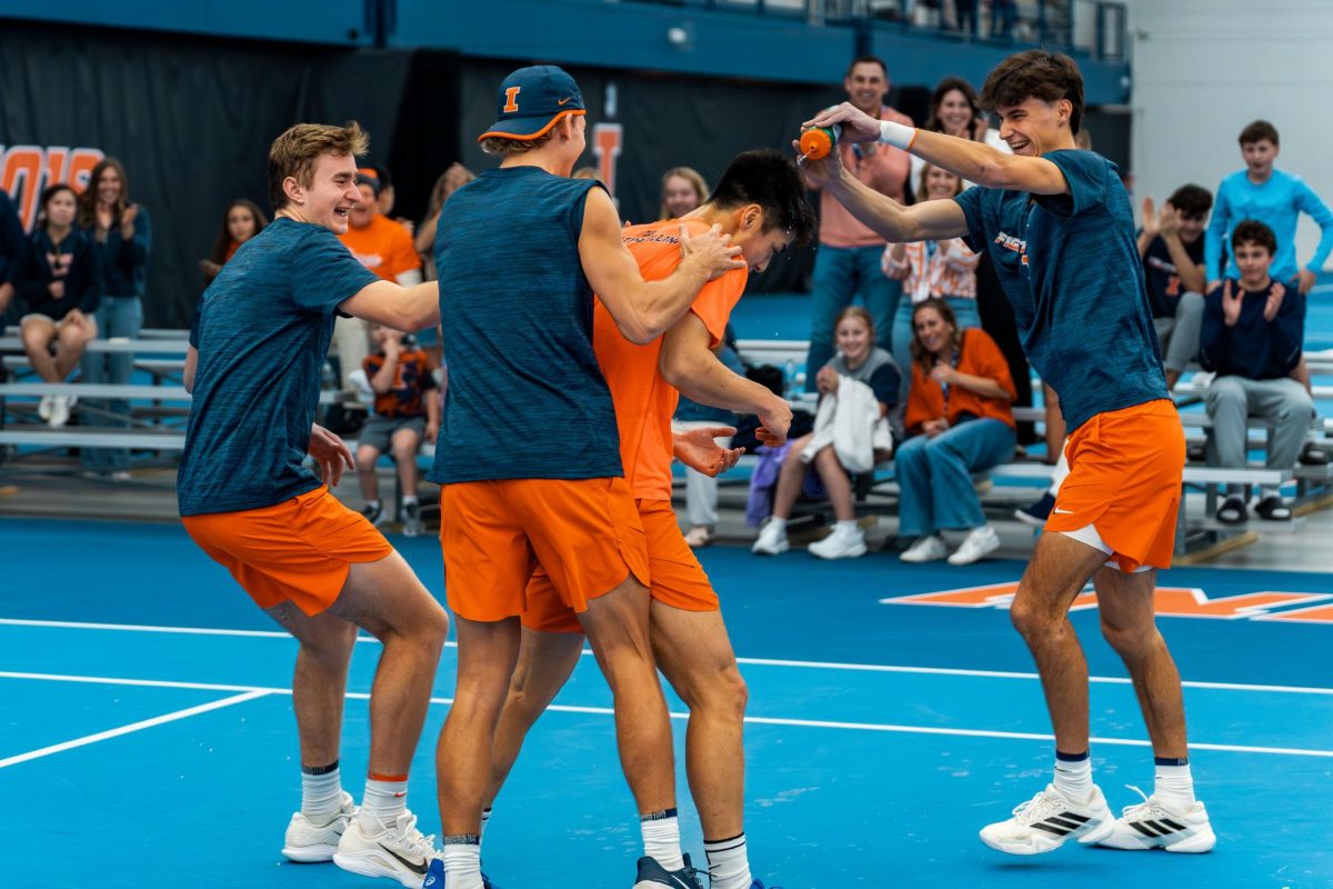 Freshman Adam Jilly (Left), redshirt junior Tyler Bowers (center) hold senior Kenta Miyoshi (Orange) as Freshman Gabriel Debru (Right) dowses the senior in water.