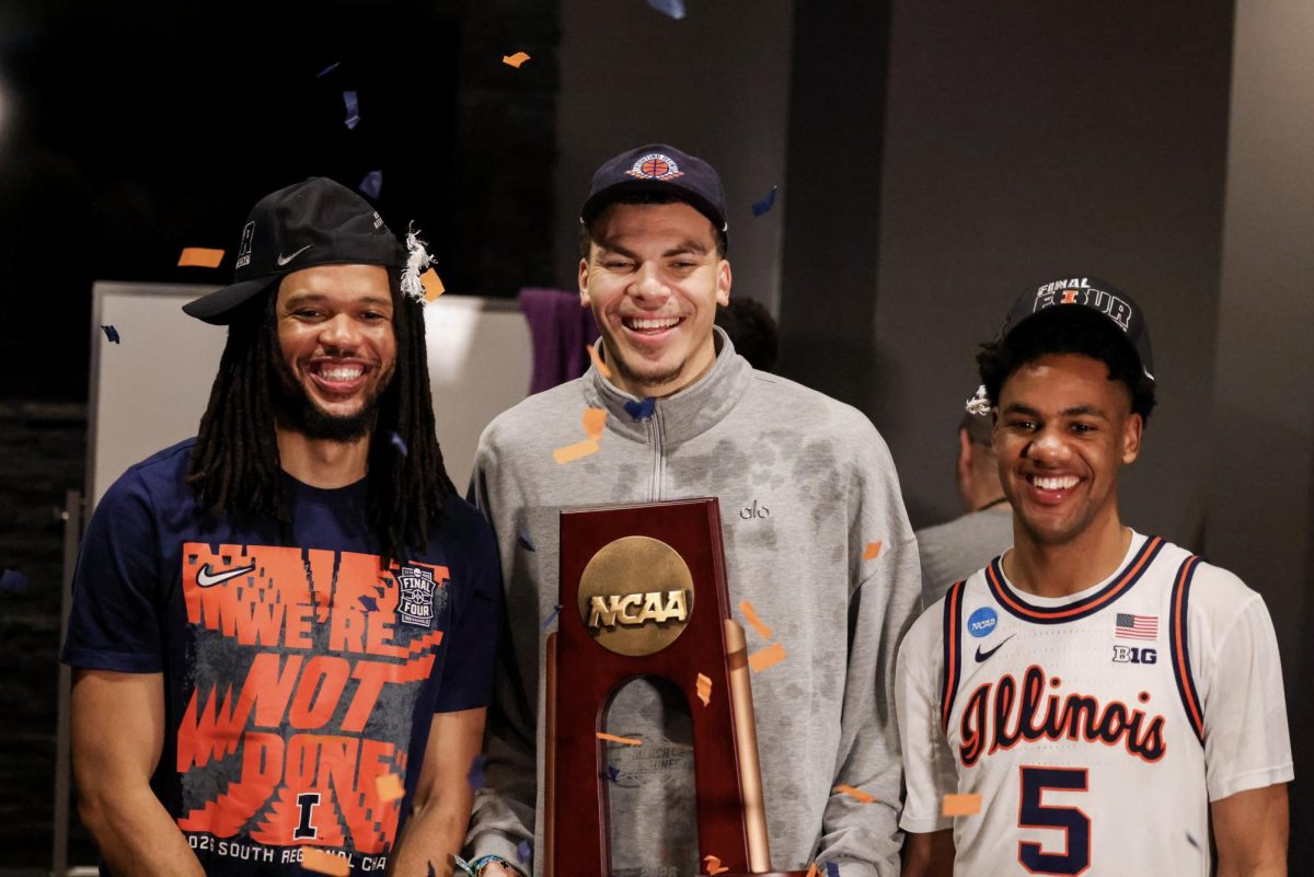 Redshirt junior guard Ty Rodgers, former Illini forward Coleman Hawkins and senior guard AJ Redd pose in the locker room at Toyota Center with the NCAA tournament South Regional trophy after Illinois advanced to the Final Four. Hawkins, Redd and Rodgers were teammates on Illinois’ 2024 Elite Eight team.