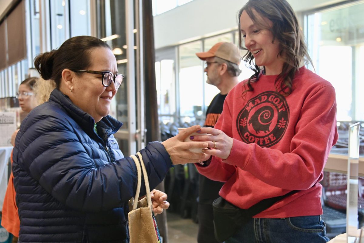 A customer samples a warm cold brew, a Mad Goat specialty, on Feb. 28. She and the vendor discuss where the company sources its coffee beans and the drink’s richness.