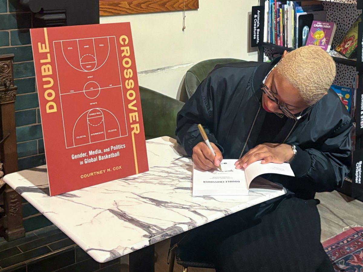 Courtney M. Cox signs a copy of her book “Double Crossover: Gender, Media, and Politics in Global Basketball,” for one of the attendees of her talk at The Literary on March 24.