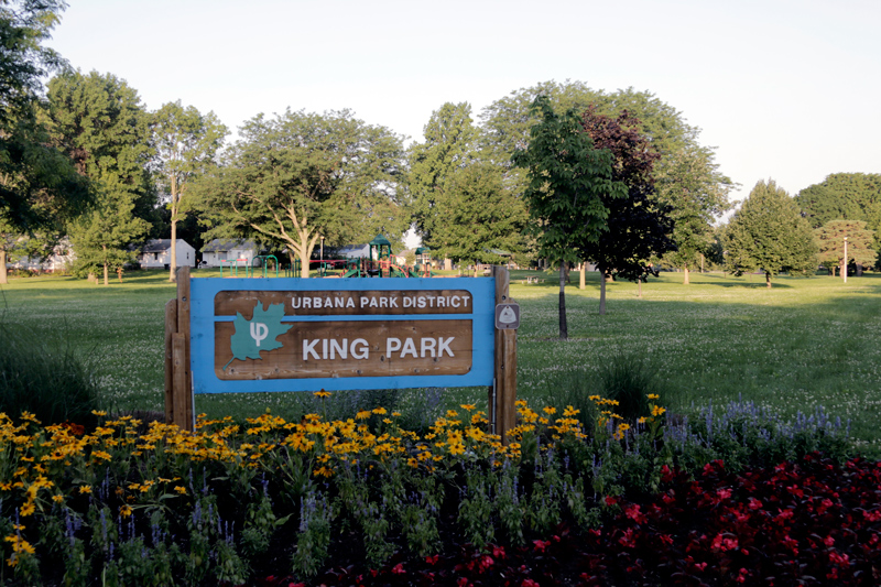Flowers bloom under a sign for Urbana Park District’s King Park. Urbana and Champaign park districts are partnering for a “March for Peace” in honor of Martin Luther King Jr. on April 4.