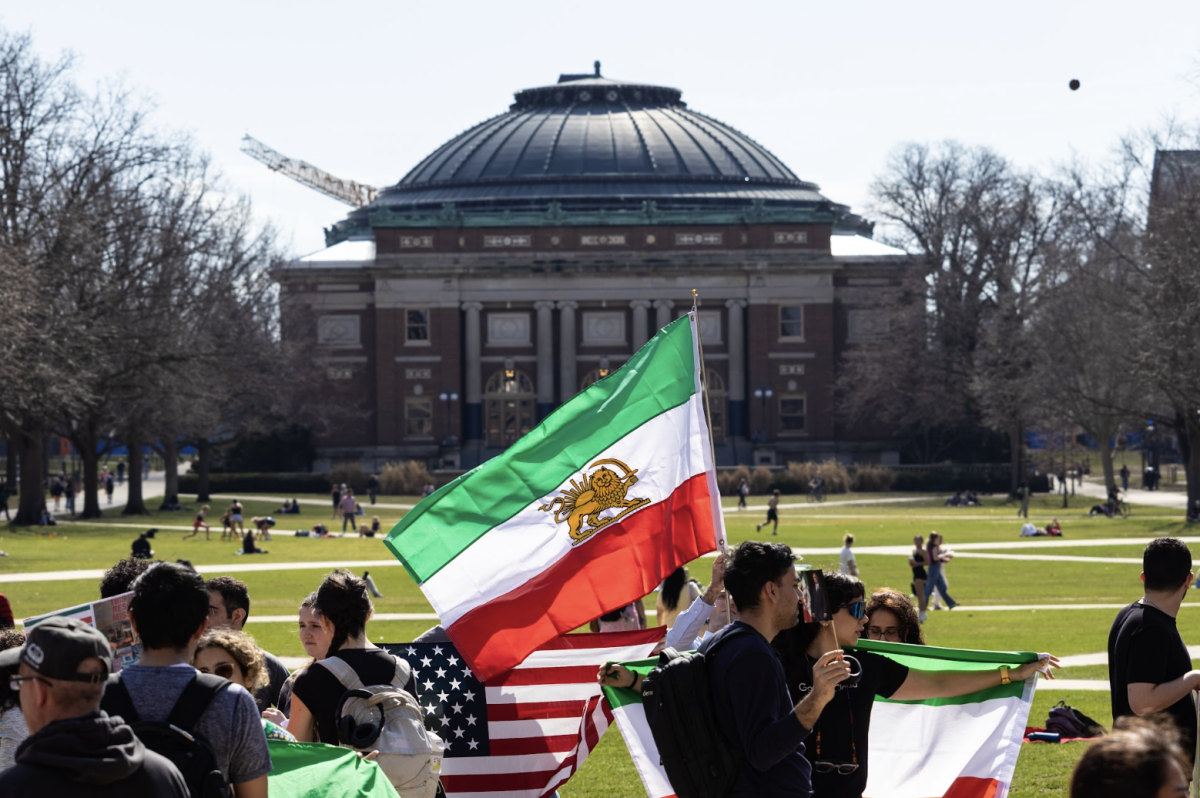 An Iranian community member flies Iran’s former “Lion and Sun” flag at a gathering at Anniversary Plaza Friday.