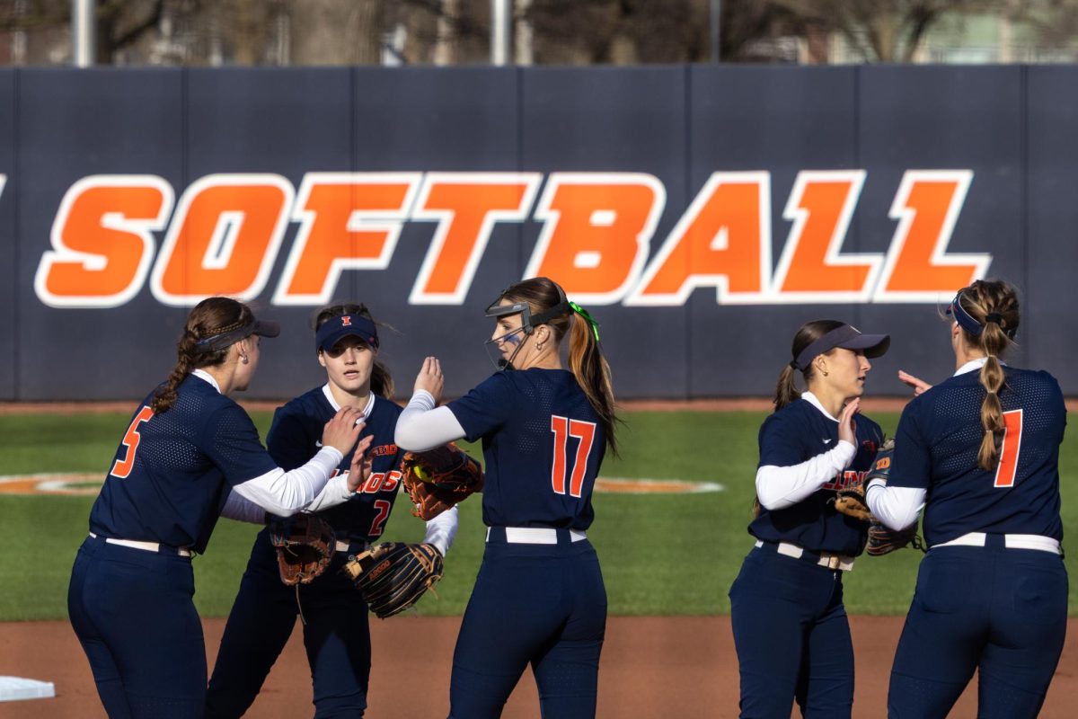 The Illinois softball team's infield high five each other before the start of the inning on March 13 at their first home game of the season against Iowa. The Illini fell to the Hawkeyes 15-21.