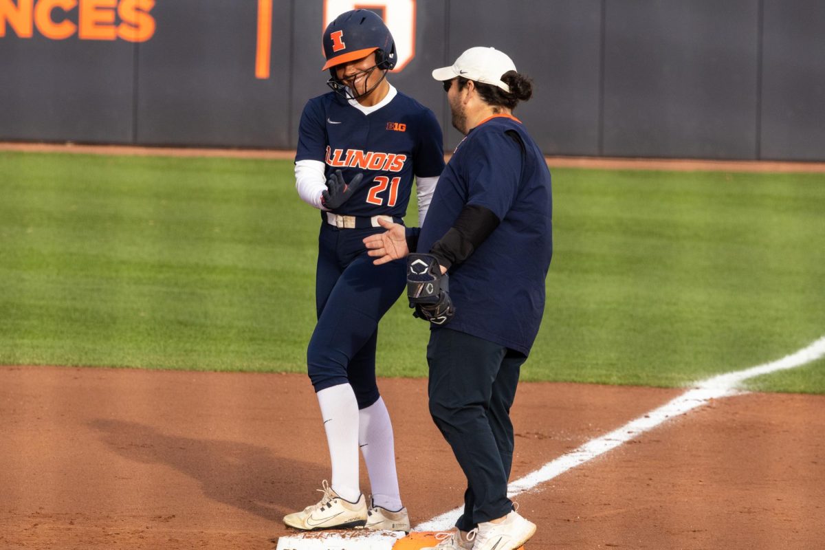 Junior outfielder Delaney Mosley high fives the first base coach on March 13 at the team’s first home game of the season against Iowa. The Illini fell to the Hawkeyes 21-15.