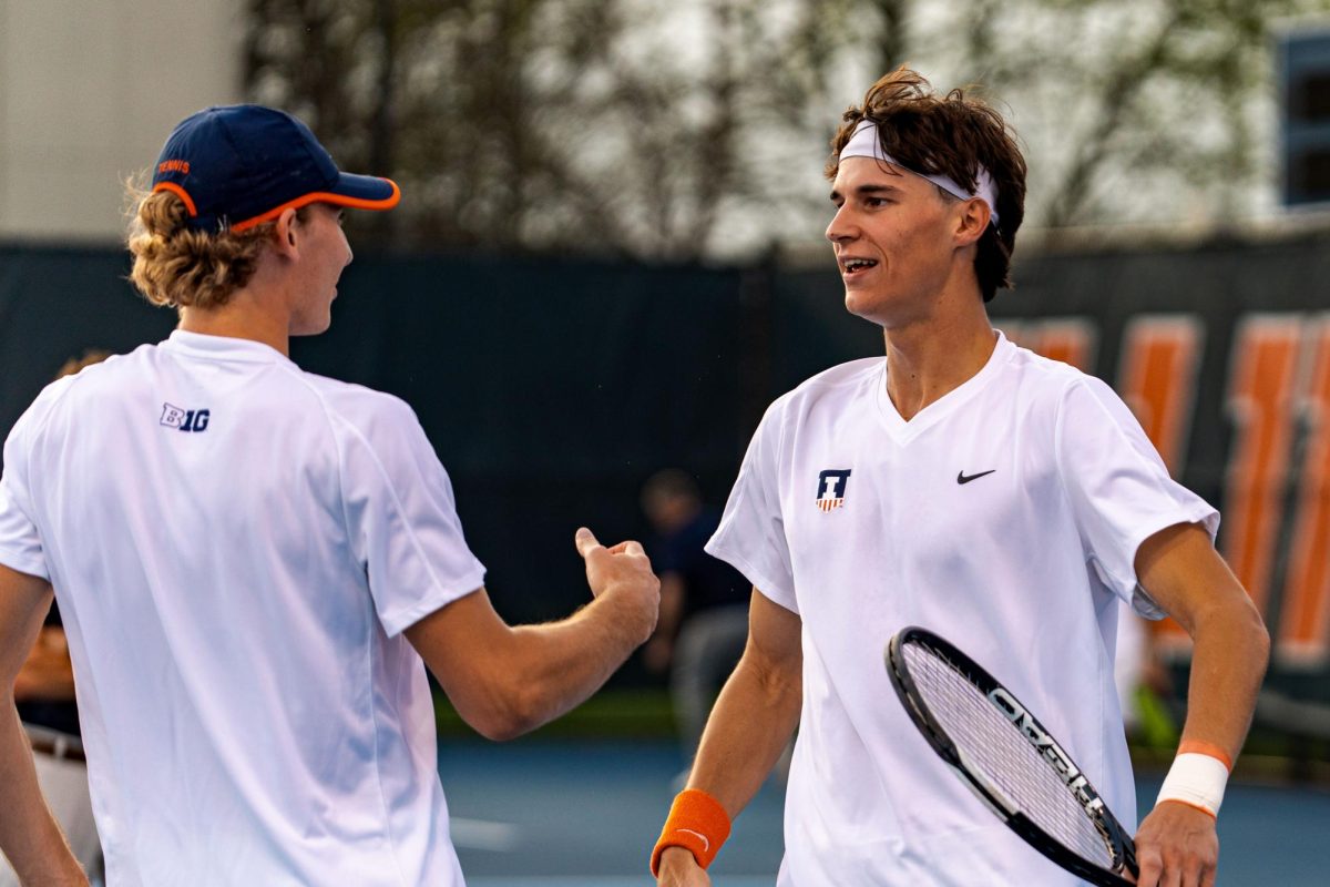 Redshirt junior Tyler Bowers (left) hive fives Freshman Gabriel Debru (Right) after a hard earned point at Atkins Tennis Center on Apr 3.