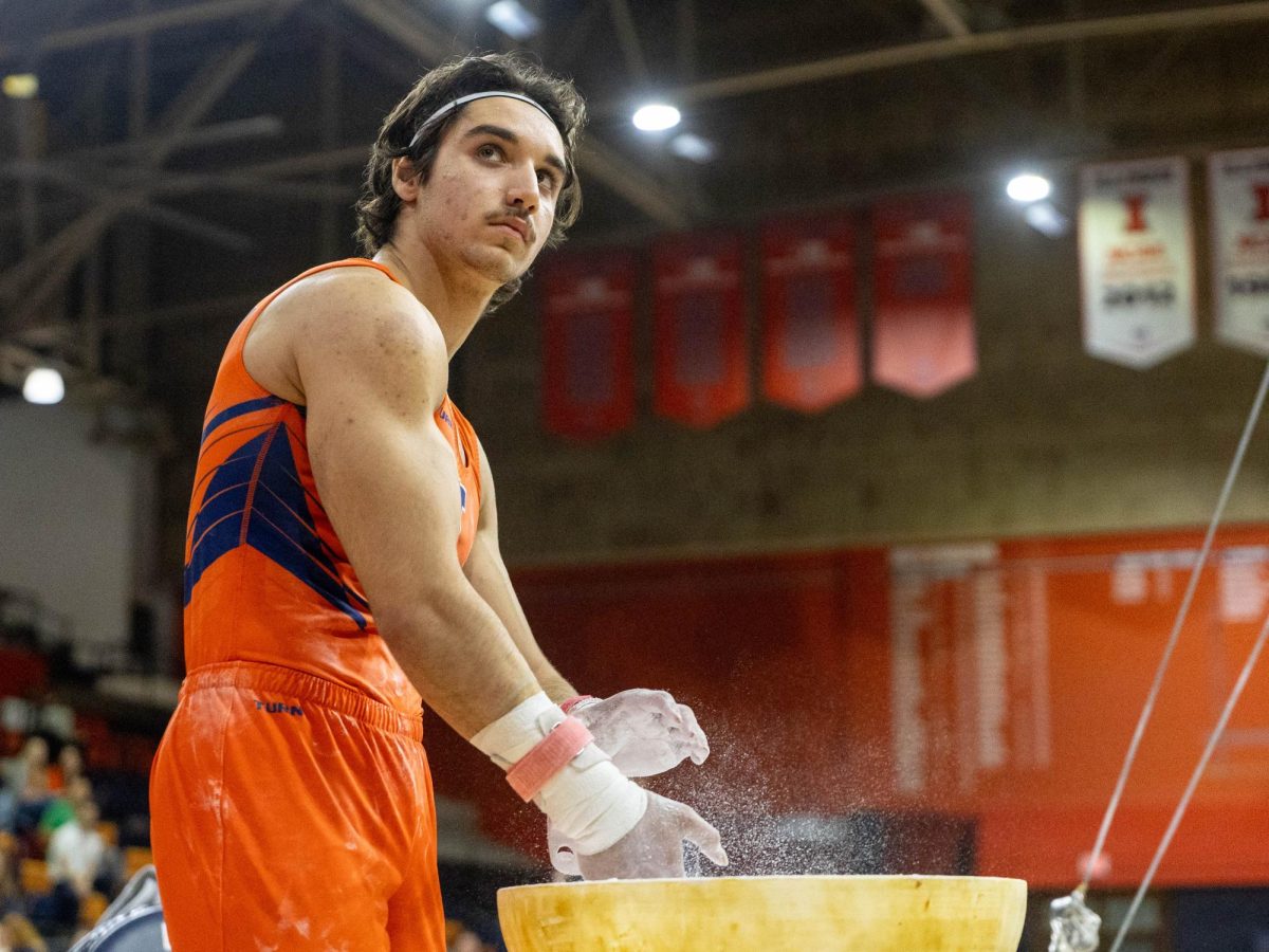 Sophomore Hasan Aydogdu chalks his grips before performing his still rings routine against Ohio State University on Mar 7 in Huff Hall.