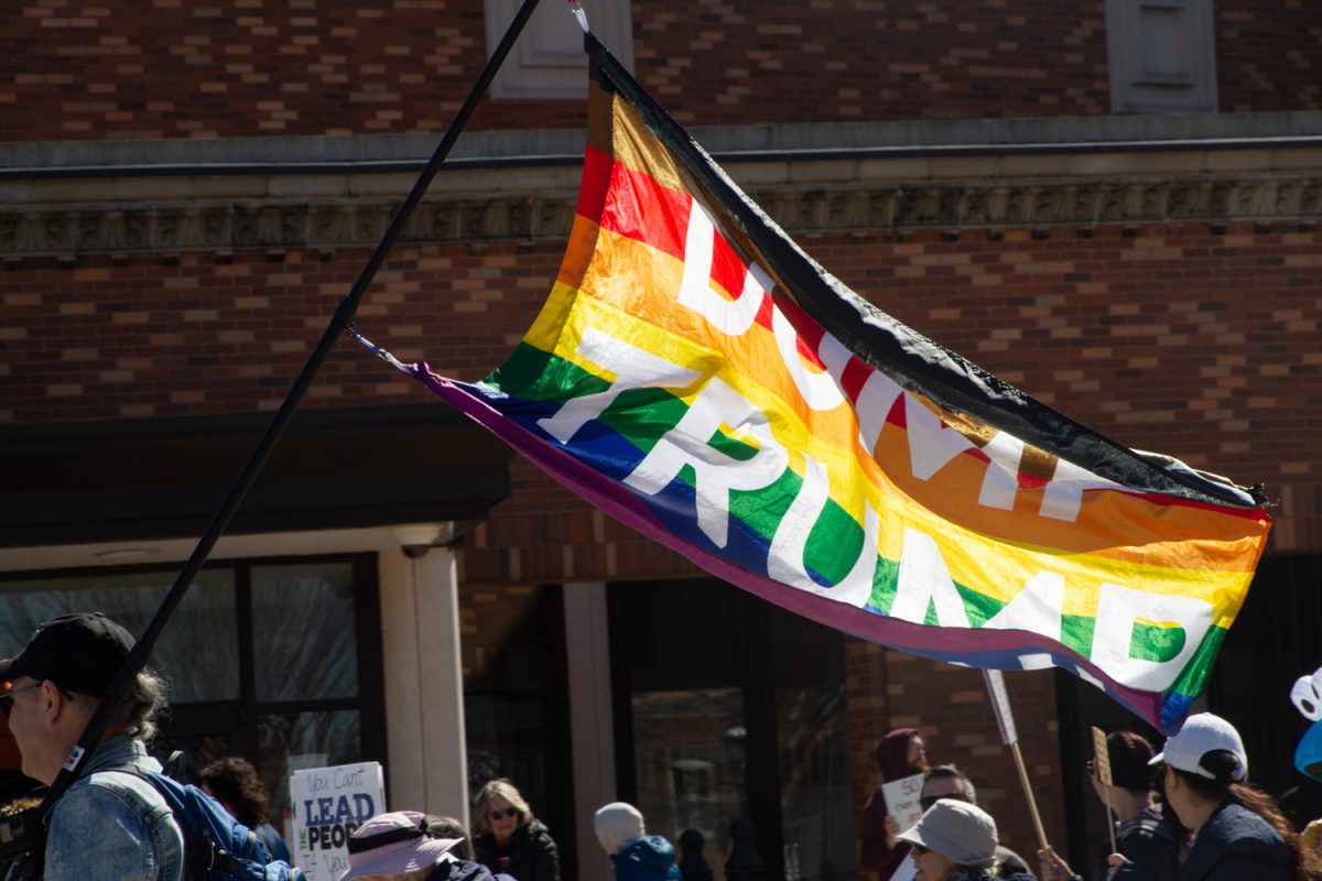 A protester flying a "Dump Trump" LGBTQIA+ flag finished his march during the 3rd No Kings protest outside of Champaign County Courthouse on Saturday, March 28.