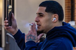 A man watches and films hundreds of protesters as they march down Green Street on Jan. 30. The crowd drew the attention of many people who live and work along the highly-trafficked roadway.