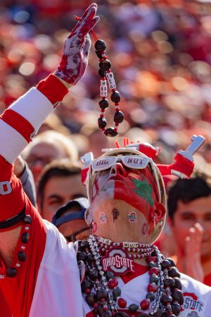 Jon Peters, an Ohio State superfan who goes by the alias Big Nut, kisses his handmade buckeye necklace at the game versus Ohio State Oct. 11. Big Nut has used his popularity to give out thousands of dollars in scholarships to Ohio high schoolers.