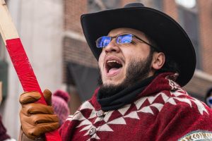 A protester waving a flag yells out the chants with a crowd of hundreds as they march through Green Street during the walk out against ICE protest on Jan. 30.