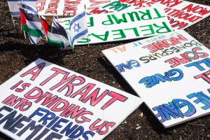A variety of protest signs lay on the ground amongst both Palestinian and Israeli flags at the 3rd No Kings protest outside of the Champaign County Courthouse on Saturday.