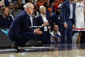 UConn head coach Dan Hurley squats low to watch the final moments of the Final Four game from the sideline.